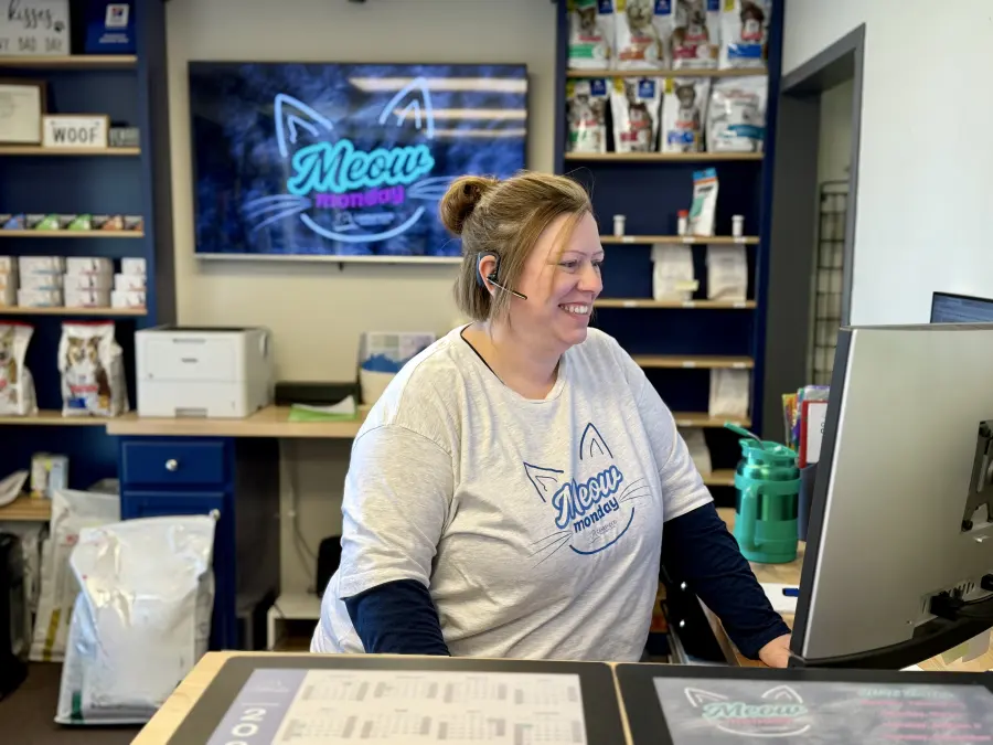 The front desk on Meow Monday, with the Meow Monday sign on the screen behind a team member